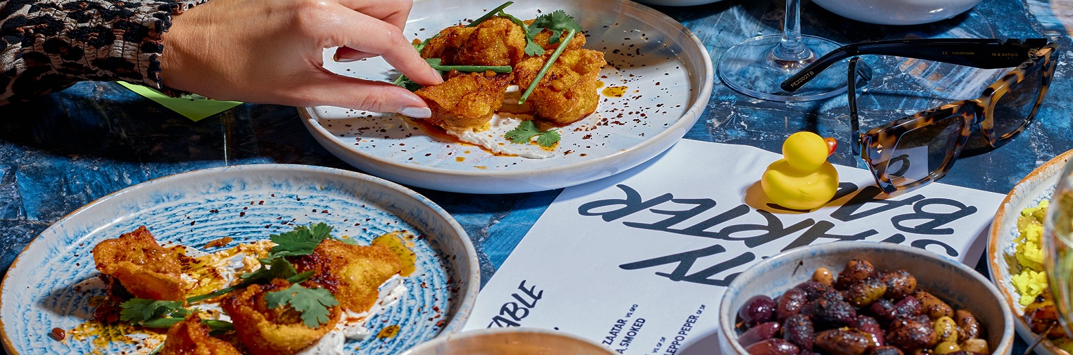 Crispy fried brunch bites served on ceramic plate with sunglasses, cocktails, and playful yellow duck – BottomlessBrunch table aesthetic
